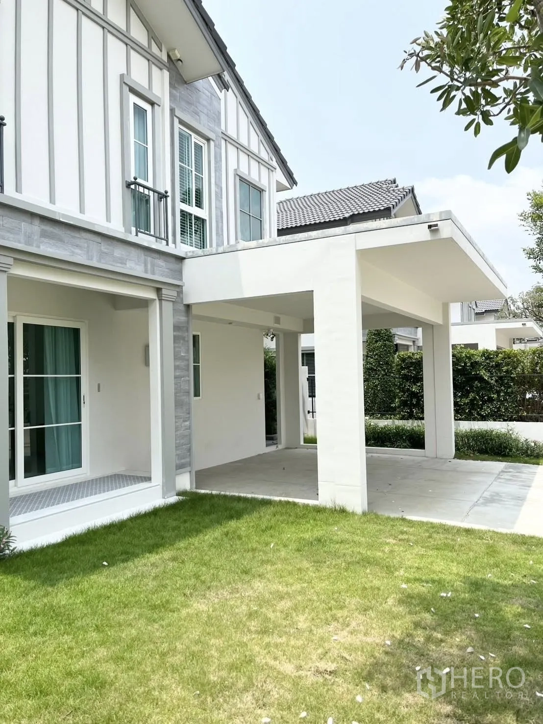 บ้านเดี่ยว for rent in Bang Phli, Samut Prakan - มุมภายนอกบ้านพร้อมสนามหญ้า ระเบียงหลังคาคลุม และผนังตัวบ้าน.