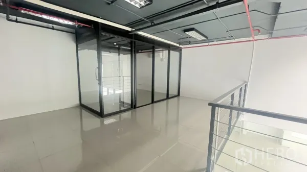 Office Space for rent in Khlong Toei, Bangkok - Mezzanine level with a glass-walled meeting room and metal railing overlooking the space below.