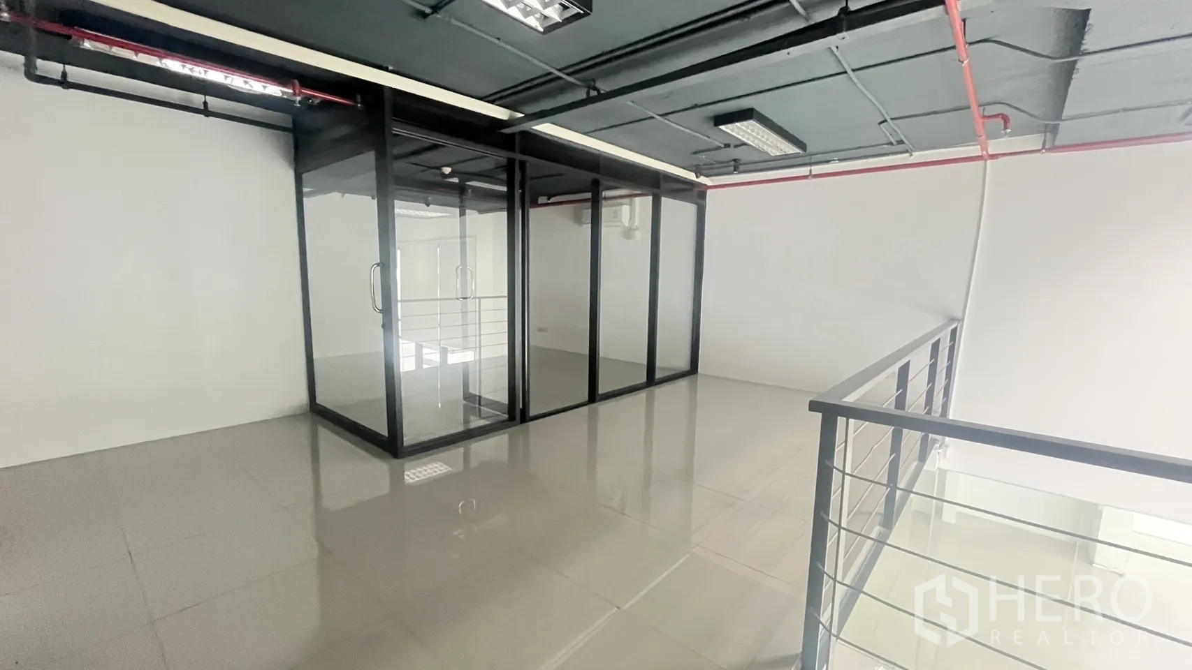 Office Space for rent in Khlong Toei, Bangkok - Mezzanine level with a glass-walled meeting room and metal railing overlooking the space below.