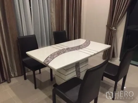 Detached House for rent in Bang Kapi, Bangkok - Dining corner with white table and four black chairs beside full-length curtains.