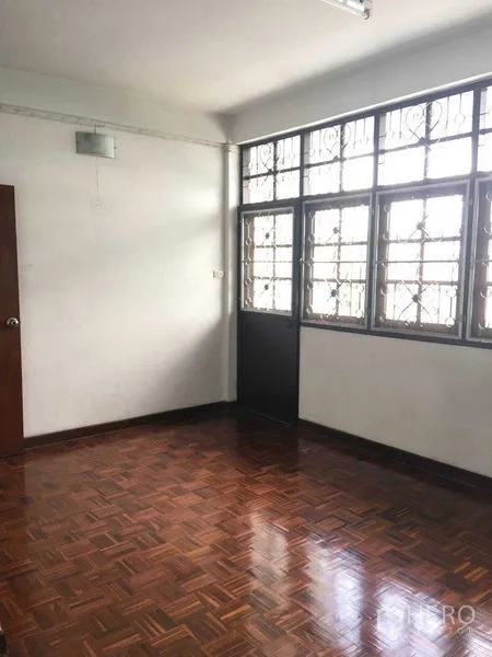联排别墅 出租在Phra Khanong, Bangkok - 明亮卧室，拼花木地板与带护栏的大窗。