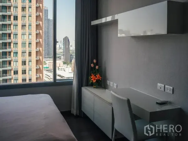 公寓 出租在Ratchathewi, Bangkok - 卧室工作区，书桌与大窗户，眺望曼谷天际线。