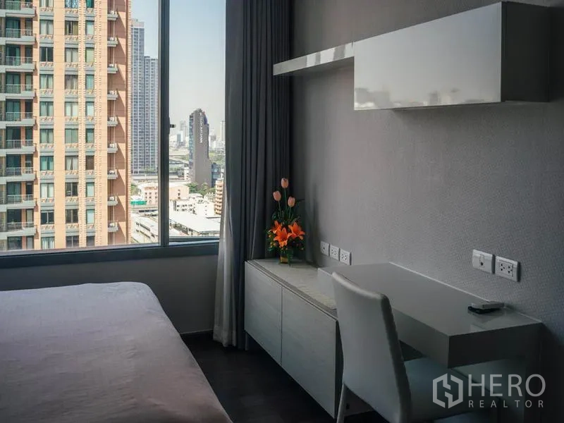 公寓 出租在Ratchathewi, Bangkok - 卧室工作区，书桌与大窗户，眺望曼谷天际线。