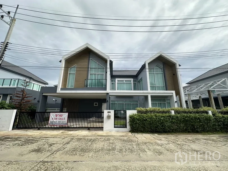 Detached House for sale in Lam Luk Ka, Pathum Thani - Modern two-storey detached house with twin gabled roofs, gated frontage and a For Sale sign.