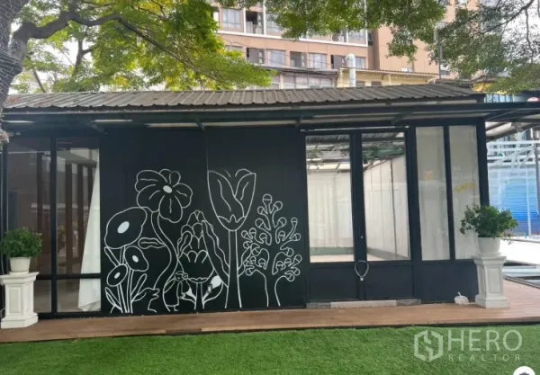 พื้นที่ขายปลีก ให้เช่าในWatthana, Bangkok - หน้าร้านกระจกติดถนน ผนังลายดอกไม้สีดำ กระถางต้นไม้และสนามหญ้า เหมาะคาเฟ่หรือบูทีค