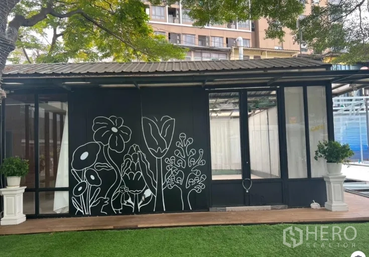 พื้นที่ขายปลีก ให้เช่าในWatthana, Bangkok - หน้าร้านกระจกติดถนน ผนังลายดอกไม้สีดำ กระถางต้นไม้และสนามหญ้า เหมาะคาเฟ่หรือบูทีค