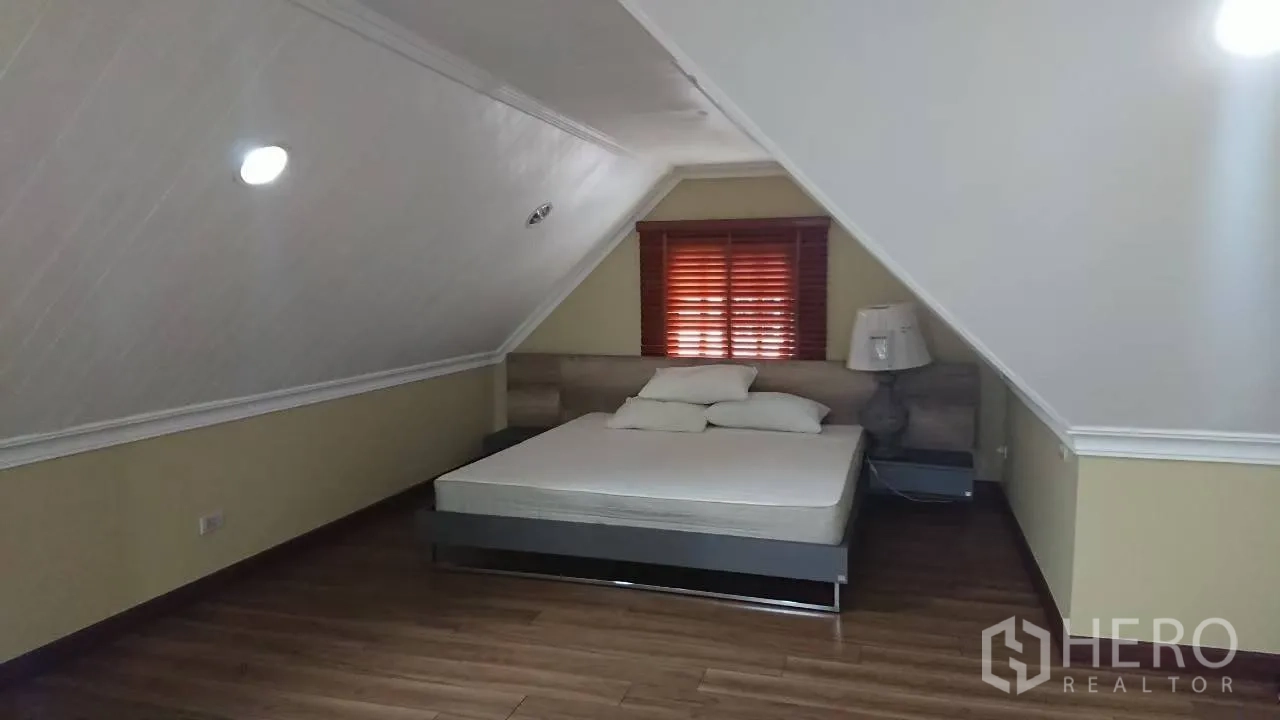 Detached House for rent in Mueang Samut Prakan, Samut Prakan - Loft-style bedroom with sloped ceiling, wood floors and a double bed.