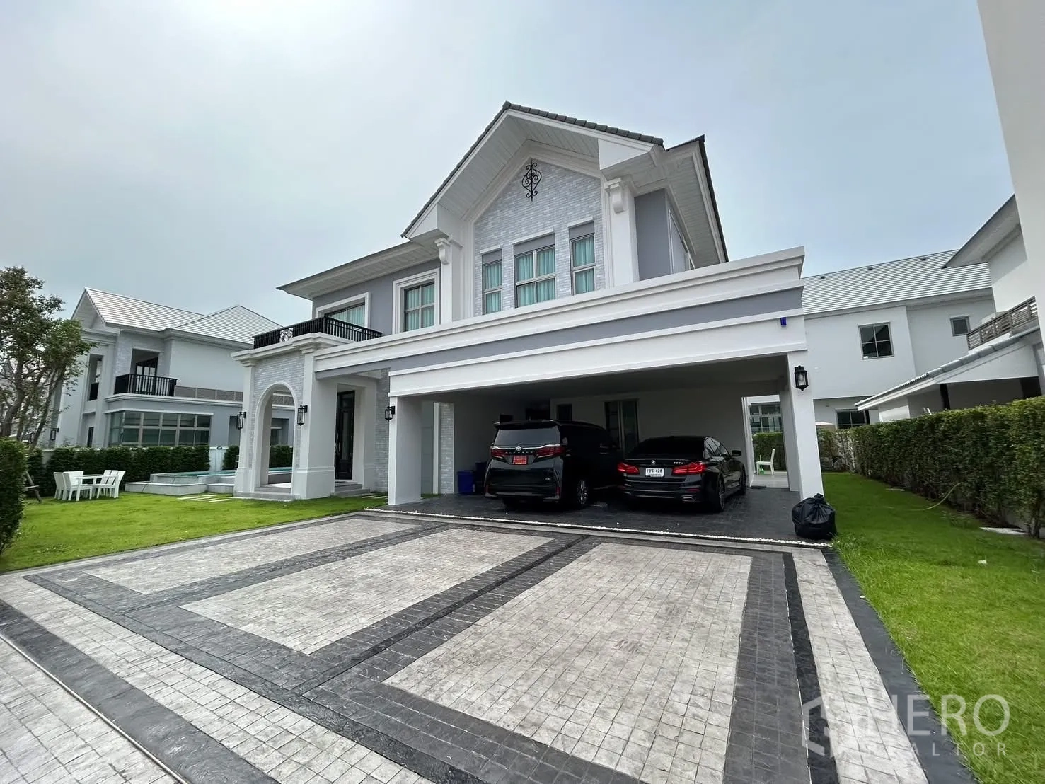 独立式住宅 出租或出售在Bang Phli, Samut Prakan - 优雅两层独栋别墅外立面，宽车道、遮雨车棚与草坪。
