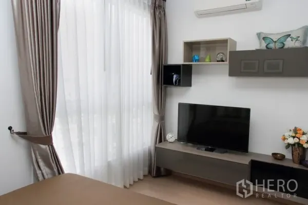 公寓 出租或出售在Watthana, Bangkok - 卧室一角，带电视柜、墙面置物格与全高窗帘。