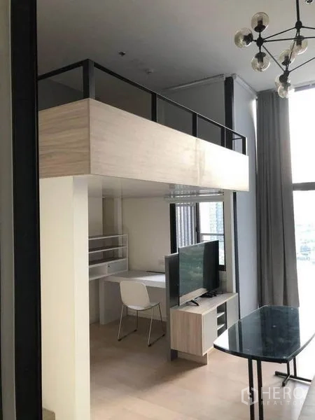 公寓 出售在Ratchathewi, Bangkok - 开放式起居区，阁楼下设书桌与电视，配玻璃餐桌。