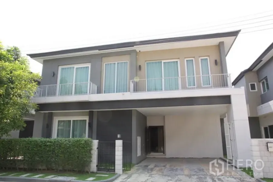 บ้าน ให้เช่าในBang Na, Bangkok - บ้านเดี่ยวสองชั้นสไตล์โมเดิร์น ย่านบางนา มีระเบียง ที่จอดรถในร่มคู่ และรั้วพุ่มไม้ด้านหน้า