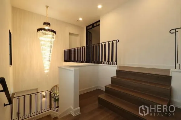 Detached House for rent in Saphan Sung, Bangkok - Stair landing with dark metal railing and a dramatic crystal chandelier.