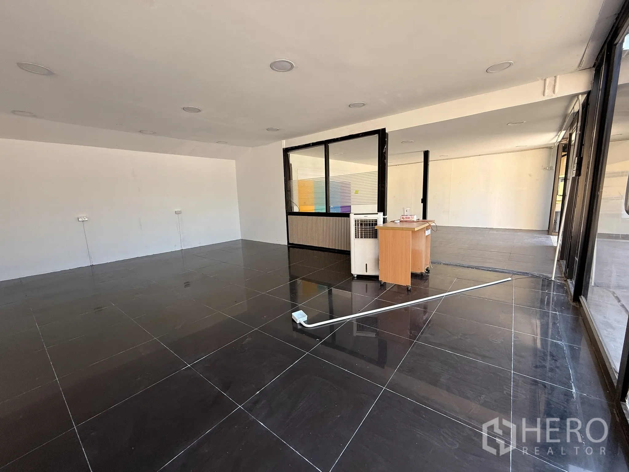 货栈 for rent in Lat Krabang, Bangkok - 开放式展厅/办公室，黑色地砖、玻璃墙与小型接待台。