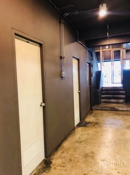 Home Office for rent in Huai Khwang, Bangkok - Hallway with white restroom doors and polished concrete floor.