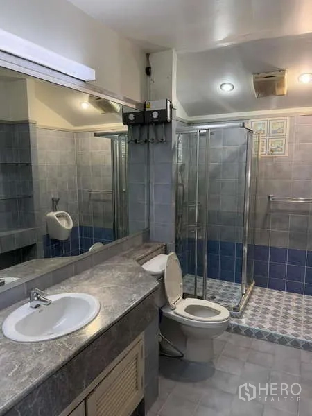 独立式住宅 出租在Bang Kapi, Bangkok - 浴室配长台面、坐便器与玻璃淋浴间。