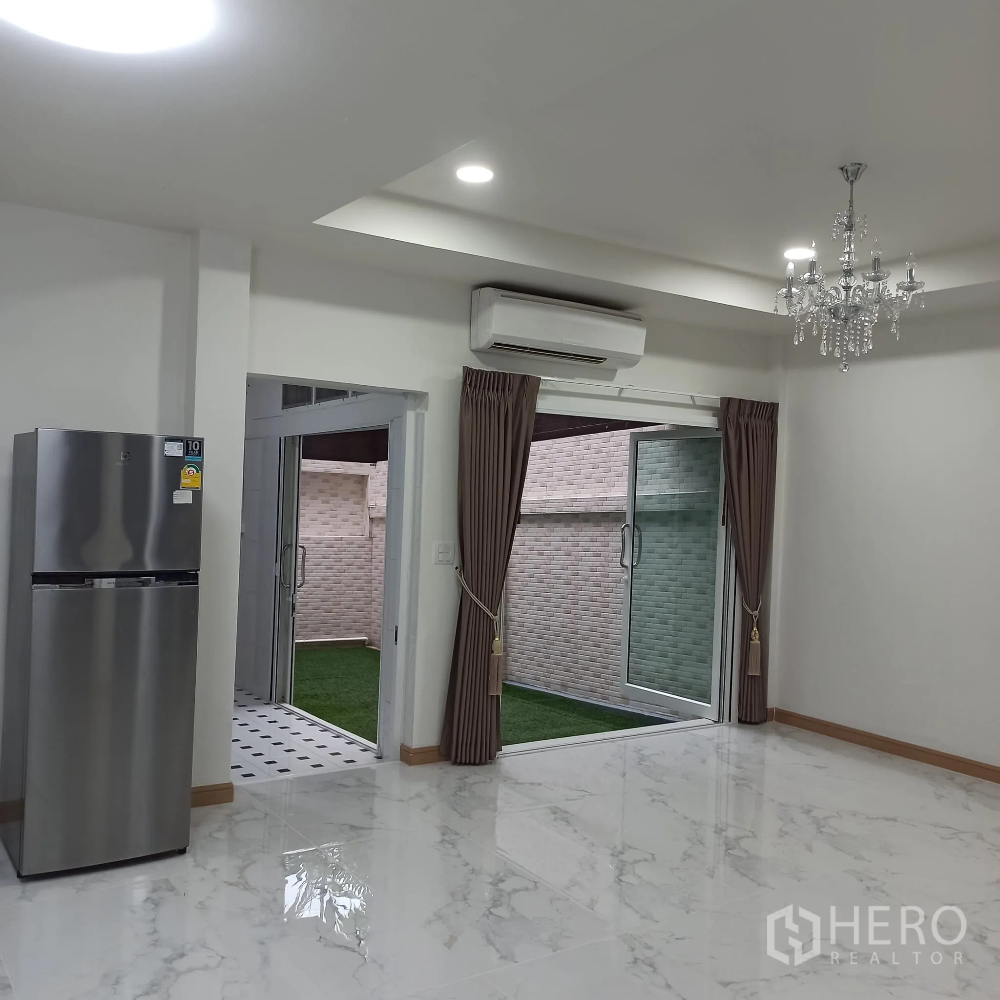Townhouse for rent in Wang Thonglang, Bangkok - Open-plan living area with chandelier and access to the courtyard.