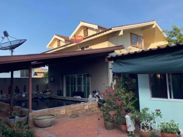 Detached House for sale in Wang Thonglang, Bangkok - Tiled backyard terrace with a raised fish pond beside the house under a lean-to roof and sliding glass doors.