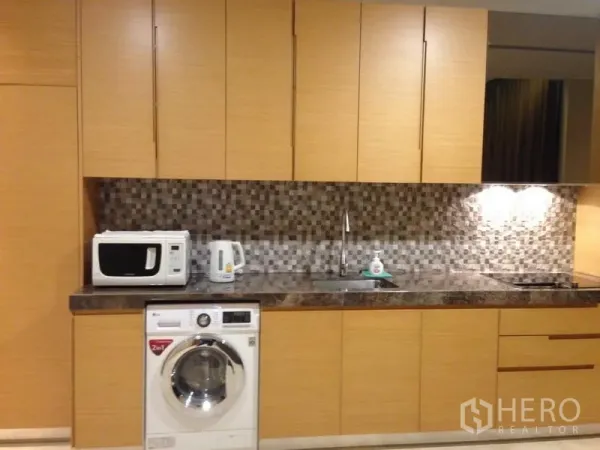Condominium for sale in Bang Rak, Bangkok - Modern kitchen with wood cabinetry, mosaic backsplash, marble countertop and in-unit washer.