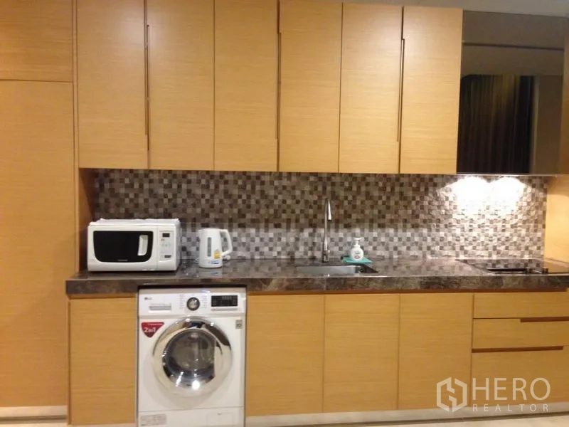 Condominium for sale in Bang Rak, Bangkok - Modern kitchen with wood cabinetry, mosaic backsplash, marble countertop and in-unit washer.