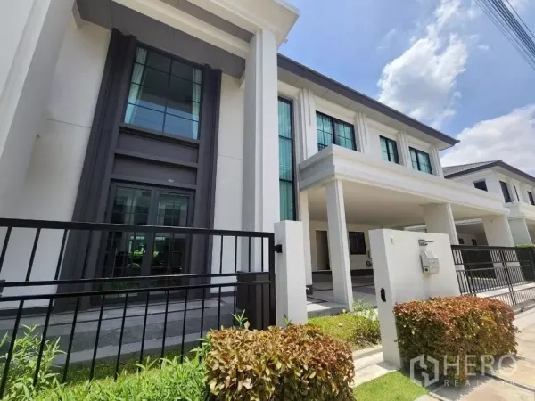 独立式住宅 出租在Bang Phli, Samut Prakan - 现代两层独栋别墅外立面，高耸立柱、院门与车道。