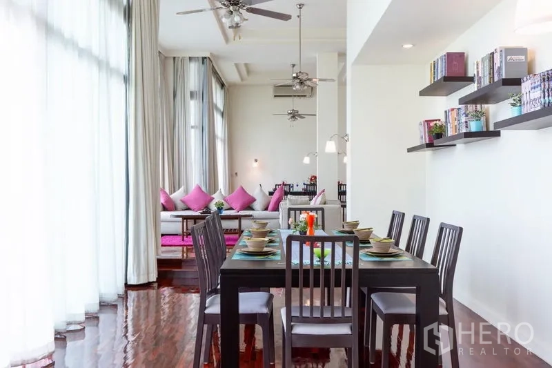 Condominium for rent in Bang Rak, Bangkok - Dining area with a six-seat table, floating bookshelves and ceiling fans beside large windows.