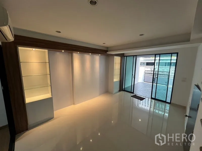 联排别墅 出租或出售在Khlong Toei, Bangkok - 一层家庭起居区，内置展示柜并通向带顶车位的推拉门。
