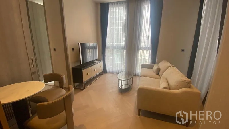 Condominium for rent - Bright living room with beige sofa, TV console and glass coffee table by floor-to-ceiling windows.