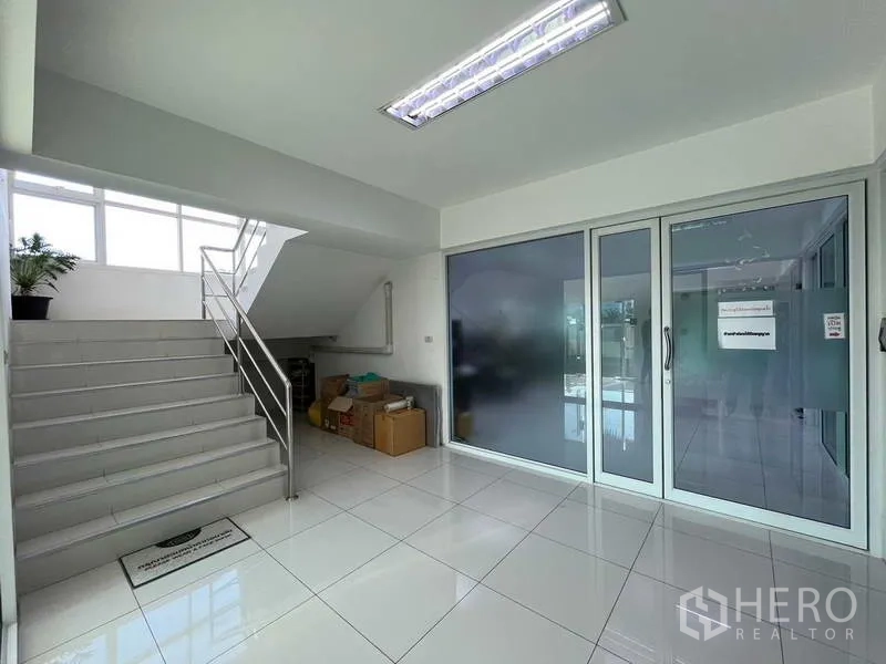 Warehouse for rent or sale in Nonthaburi - Bright lobby with white tiled floors, staircase, and glass doors leading to office suites.