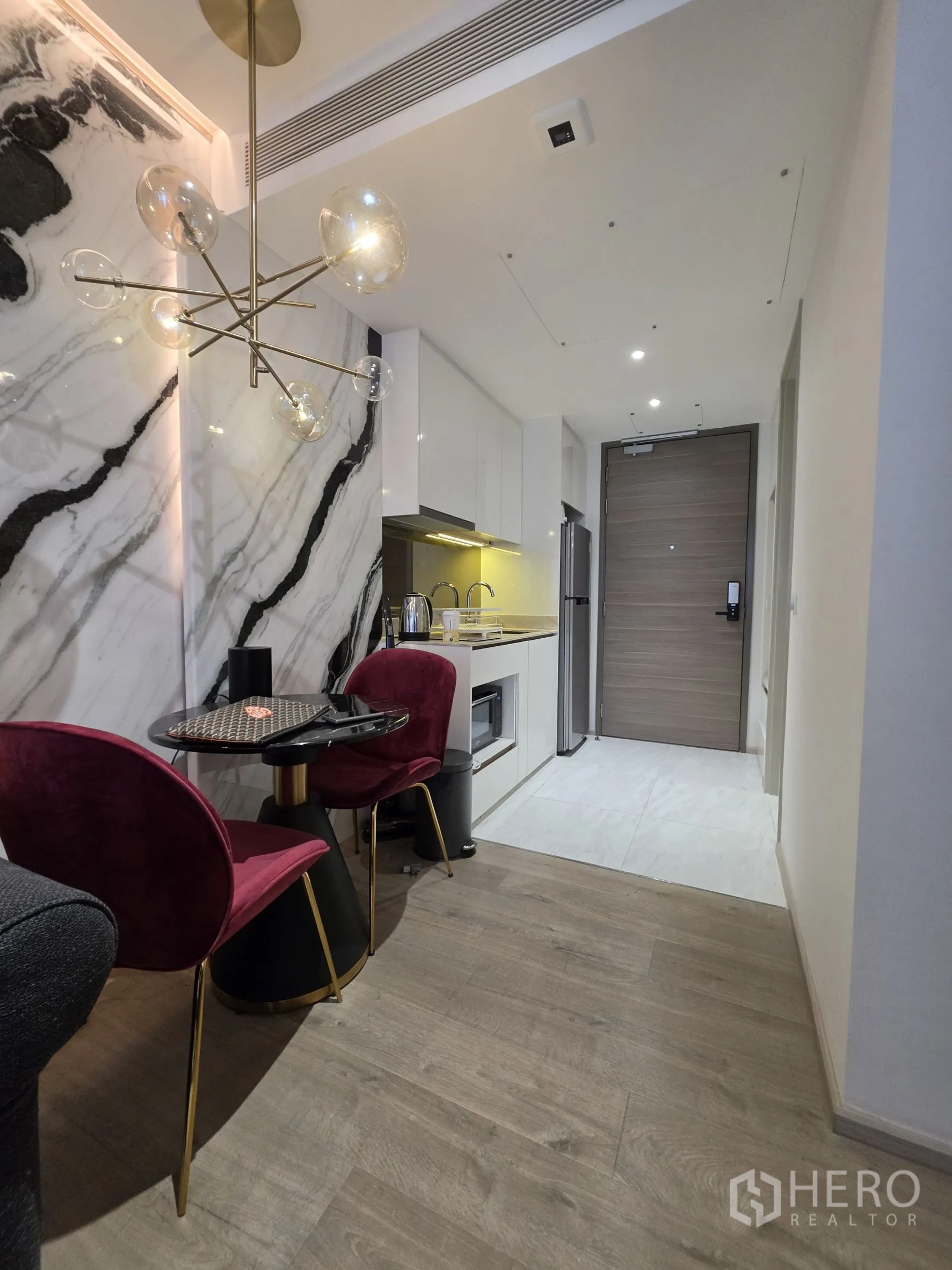Condominium for rent in Khlong Toei, Bangkok - Small dining table with two upholstered chairs beneath a sculptural pendant light.