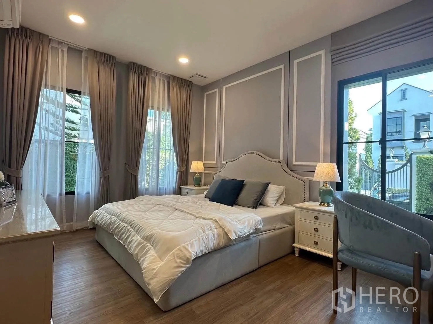 Detached House for rent in Saphan Sung, Bangkok - Guest bedroom with large windows, upholstered bed, and bedside tables.