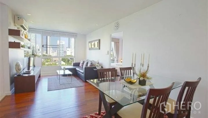 Condominium for rent or sale in Watthana, Bangkok - Open-plan living and dining area with wood floors and large window city views.