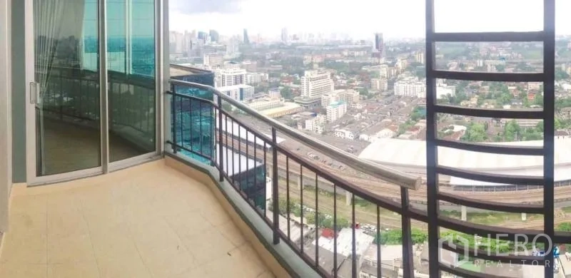 公寓 出租或出售在Huai Khwang, Bangkok - 带弧形栏杆的大阳台，推拉玻璃门外是城市全景。