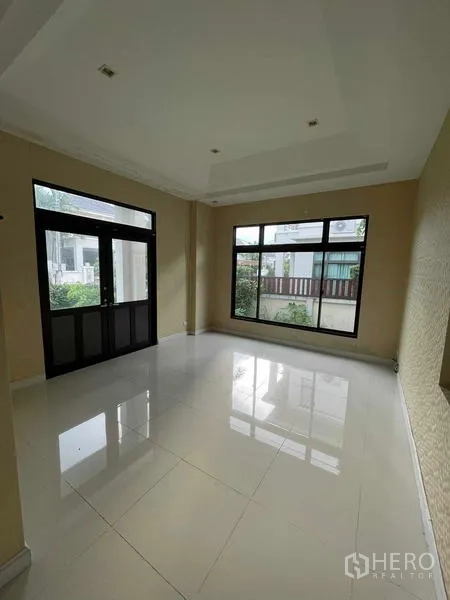 独立式住宅 出售在Lat Krabang, Bangkok - 一层客厅采光明亮，落地窗与亮面白色地砖。