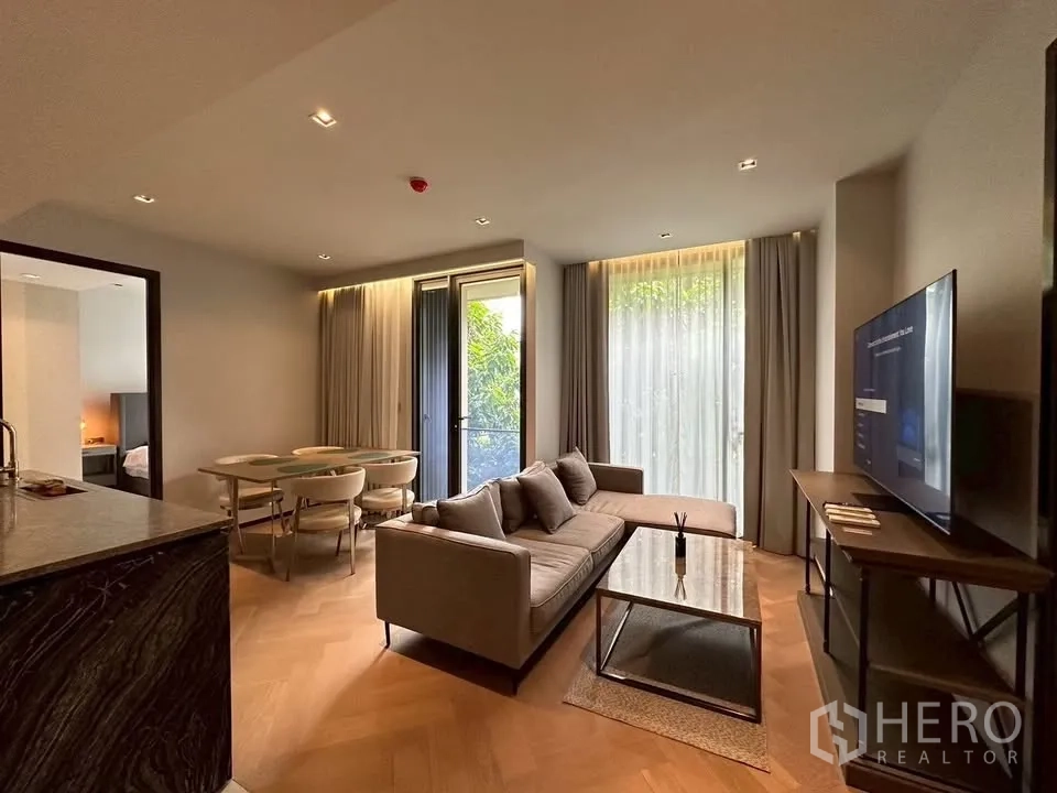 คอนโด for rent in Watthana, Bangkok - มุมนั่งเล่นสบายๆ พร้อมทีวี โซฟา และผ้าม่านโปร่งรับทิวทัศน์สีเขียว.