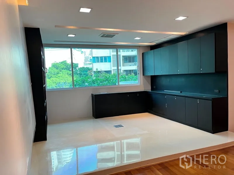 公寓 出租在Khlong Toei, Bangkok - 多功能房配长排黑色柜体与大窗，眺望城市景。