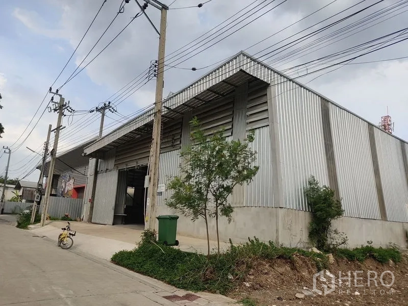 Warehouse for rent in Bueng Kum, Bangkok - Street view of corrugated metal warehouse exterior in Bueng Kum, Bangkok with loading bay and driveway.