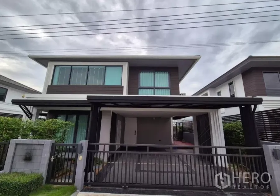 Detached House for sale in Bang Kruai, Nonthaburi - Modern two‑storey detached house facade with gated carport and hedges in Bang Kruai, Nonthaburi.