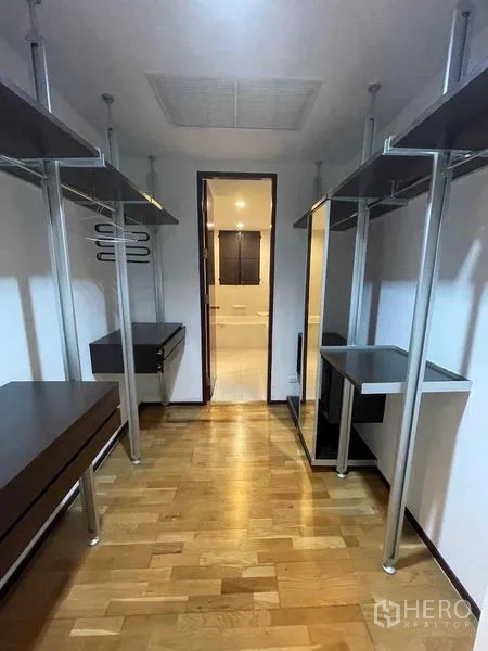 Condominium for rent in Din Daeng, Bangkok - Walk-in closet with open wardrobes and hardwood floor connecting to bathroom.