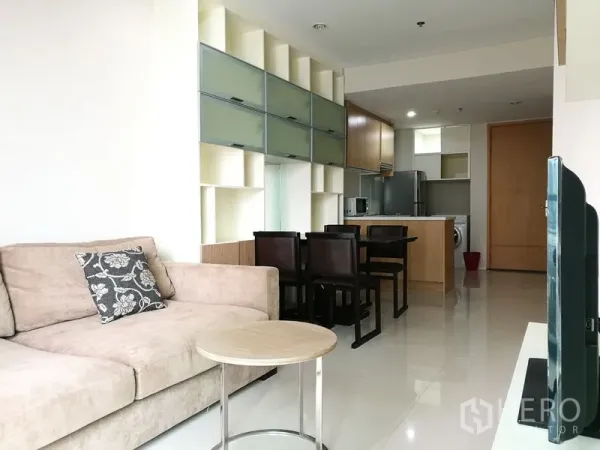 Condominium for rent in Ratchathewi, Bangkok - Open‑plan lounge with sofa, dining set and wall storage leading to a fitted kitchen.