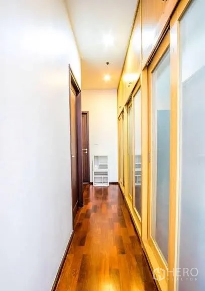 Condominium for rent or sale in Watthana, Bangkok - Well-lit corridor with built-in wardrobes and glossy wooden flooring.