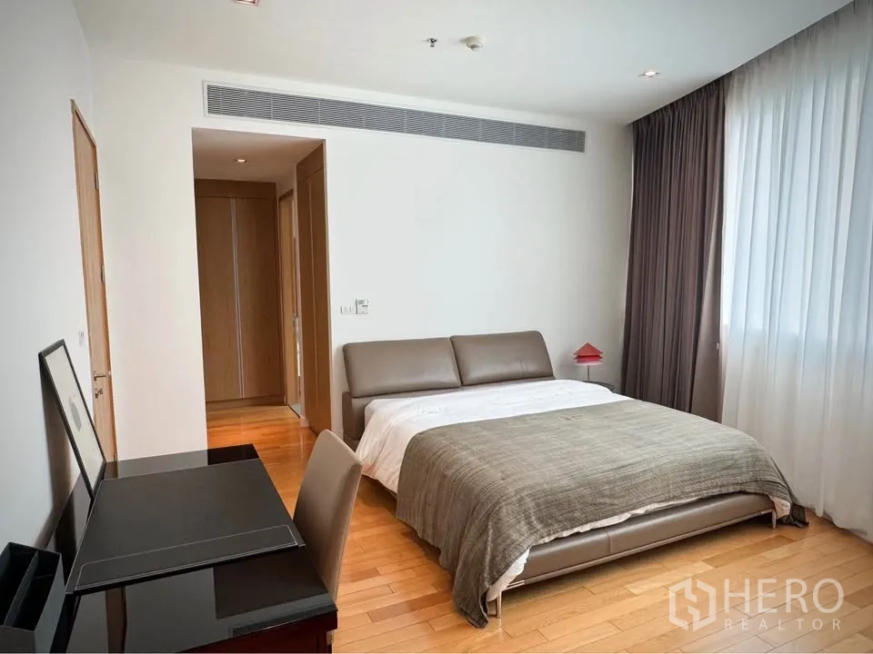 Condominium for rent or sale in Khlong Toei, Bangkok - Primary bedroom with upholstered bed, work desk, and wide curtained window.