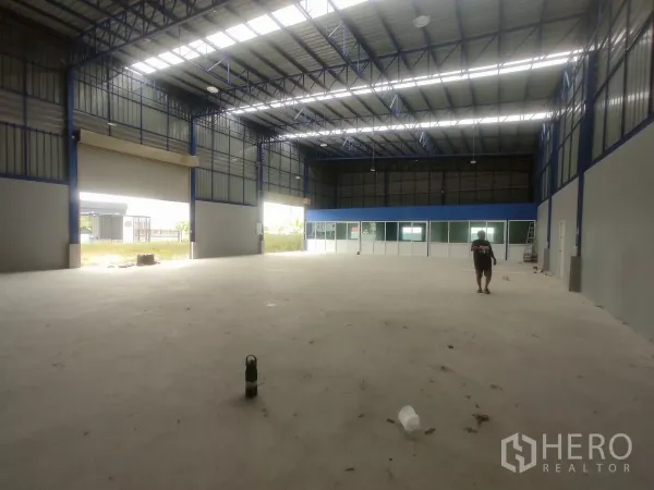 Factory for sale in Khlong Toei, Bangkok - Spacious high-ceiling warehouse interior with steel trusses, skylights and wide loading bays.