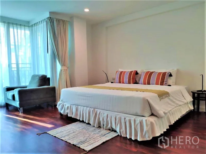 公寓 出租在Bang Rak, Bangkok - 主卧配特大床、单人沙发、薄纱窗帘与木地板。