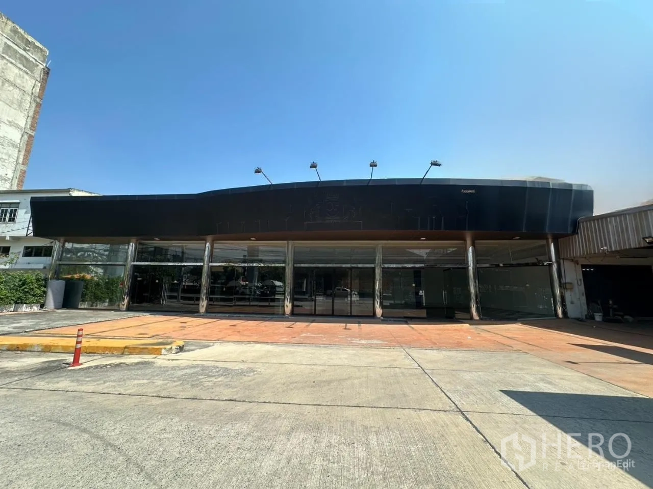 Showroom for rent in Suan Luang, Bangkok - Wide glass‑fronted showroom exterior with black canopy and open forecourt.