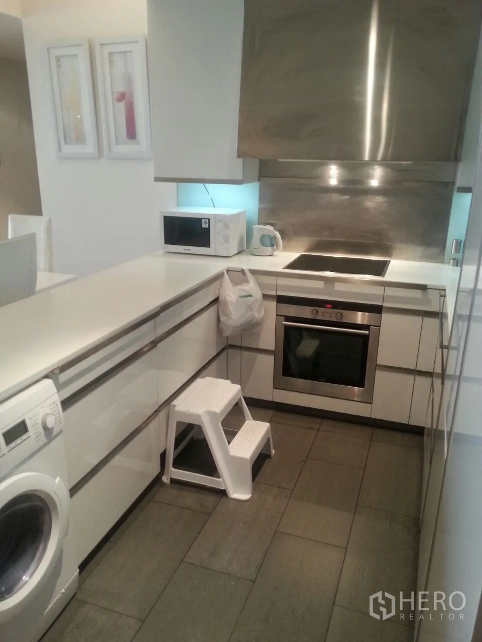 Condominium for rent or sale in Sathon, Bangkok - Modern kitchen featuring oven, cooktop, microwave and in‑unit washing machine.