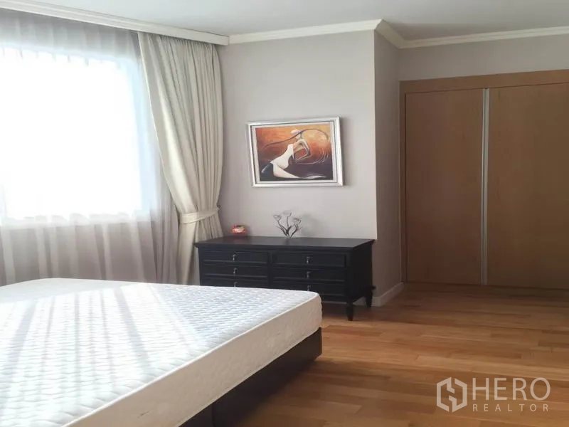 Condominium for rent in Khlong Toei, Bangkok - Second bedroom with sunny window, wardrobe, dresser and light wood floors.