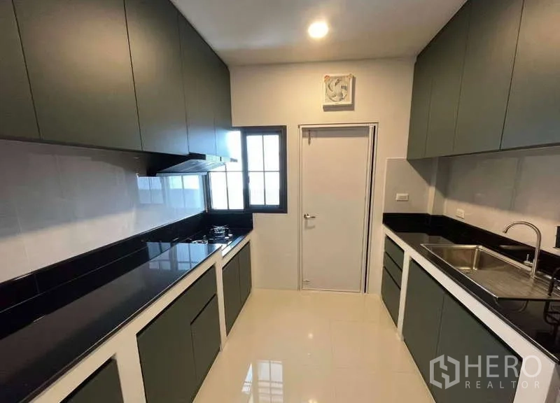 บ้าน ให้เช่าในBang Phli, Samut Prakan - ครัวสไตล์แกลเลย์ เคาน์เตอร์หินสีดำ เตาแก๊ส อ่างล้างจาน และตู้บิวท์อิน