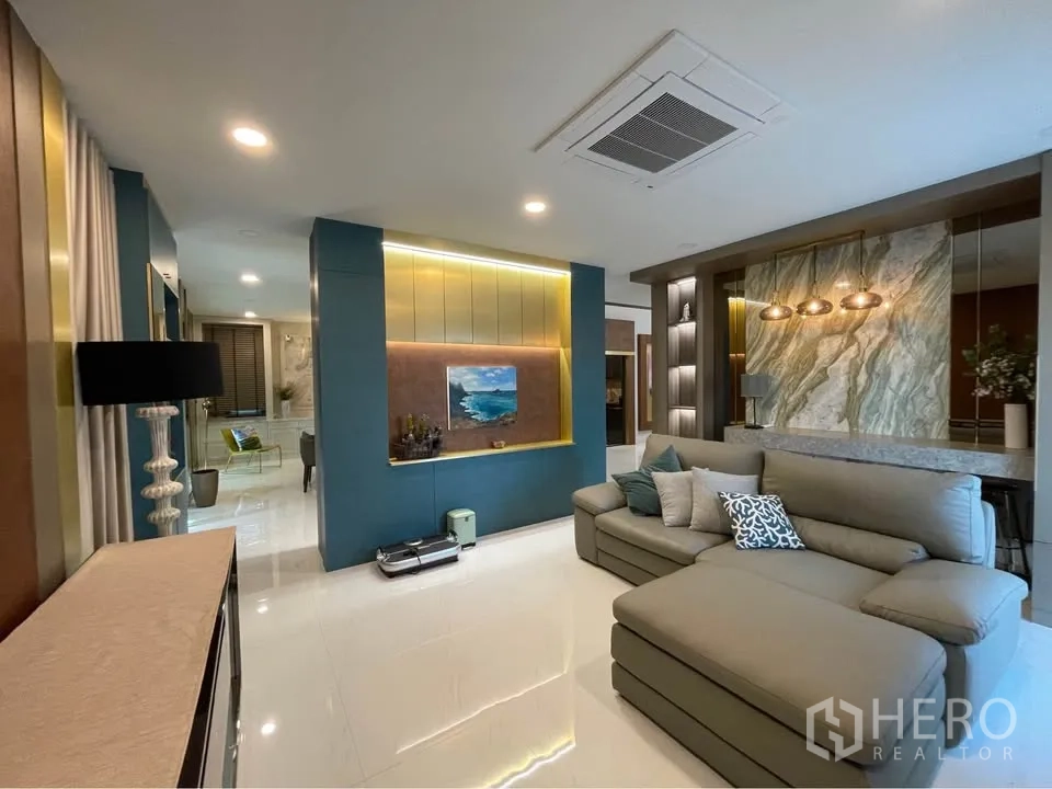 独栋房屋 for rent or sale in Bang Phli, Samut Prakan - 起居区设转角沙发、特色墙面与嵌入式空调。