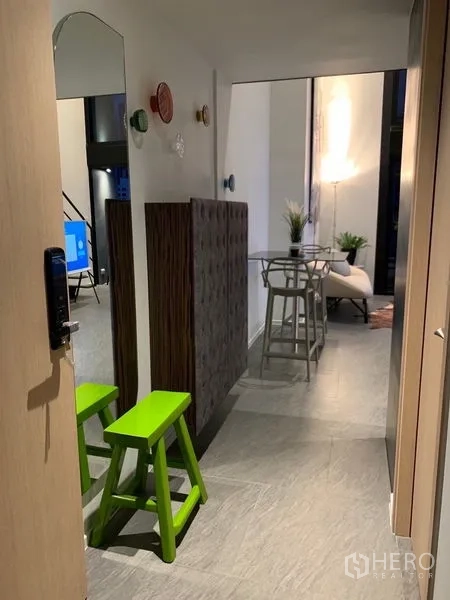 Condominium for rent in Bang Rak, Bangkok - Entry hallway with green stools and decorative wall accents leading to living space.