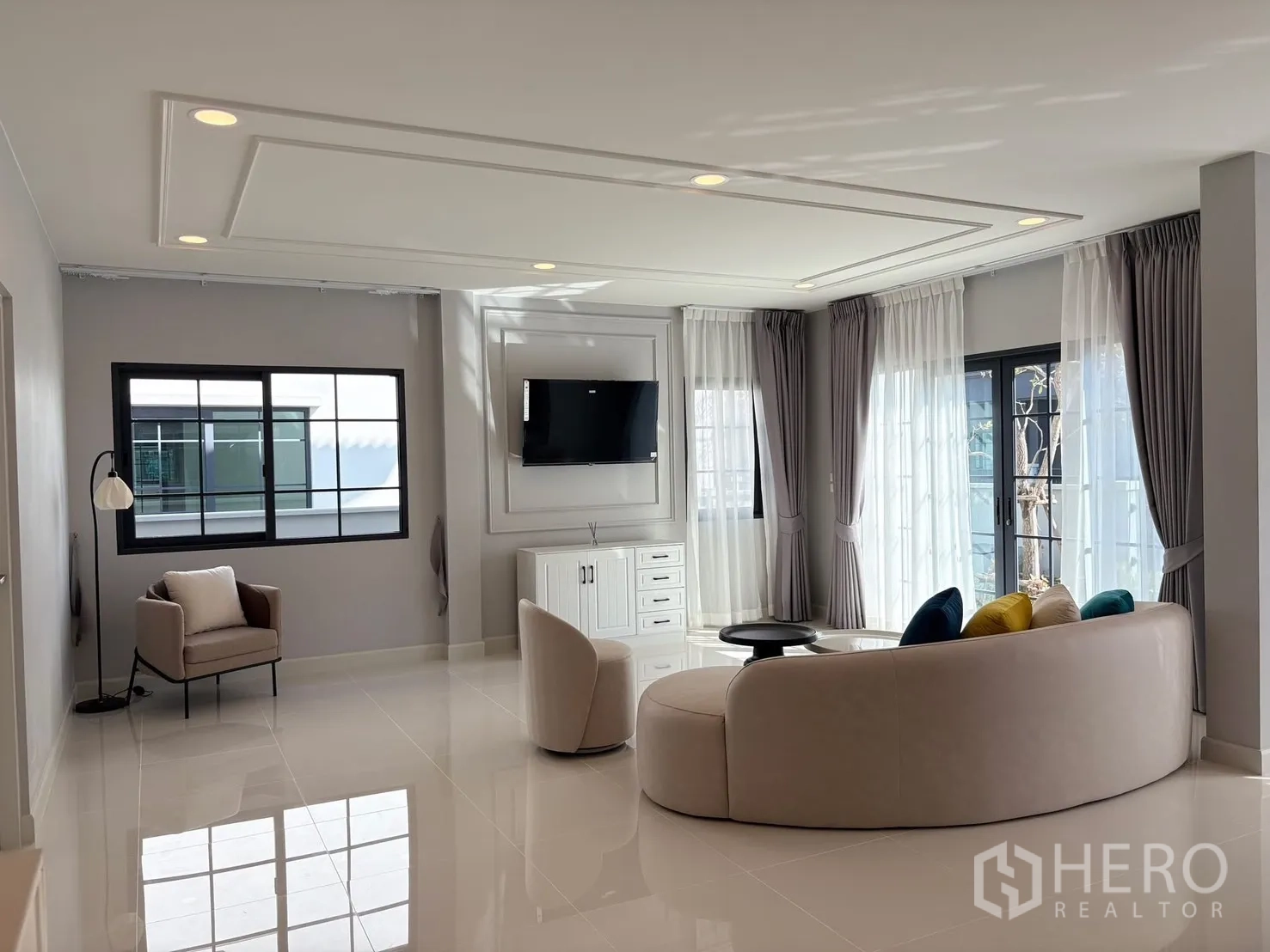 บ้าน for rent in Bang Phli, Samut Prakan - ห้องนั่งเล่นกว้าง โซฟาโค้ง ผนังติดทีวี กระจกบานใหญ่และพื้นกระเบื้องเงา.
